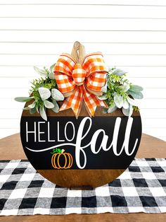 a black and white checkered table cloth with a wooden sign that says hello fall