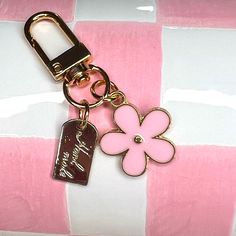 a pink flower keychain with a tag attached to it