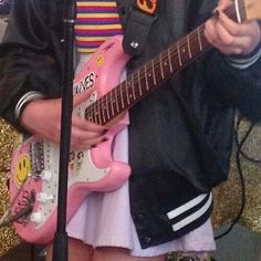 a person with a pink guitar in front of a microphone