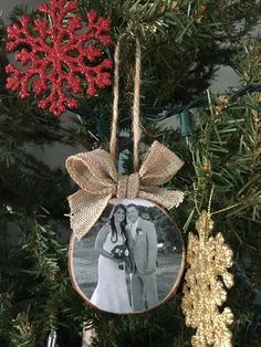 an ornament hanging from a christmas tree with a photo on it and a snowflake in the background