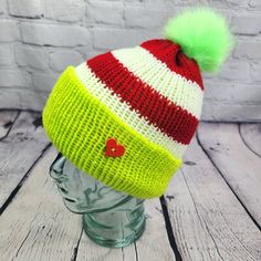 a knitted hat with a green and red pom - pom on top