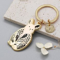 a gold keychain with a dog on it sitting next to a white flower