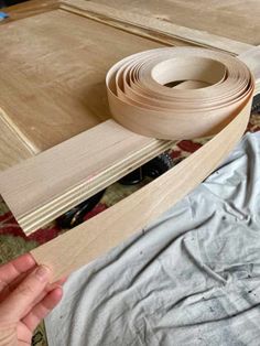 a person is holding a piece of wood near some pieces of plywood and tape