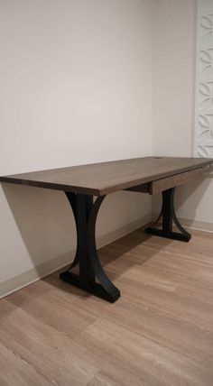 a wooden table sitting on top of a hard wood floor next to a white wall