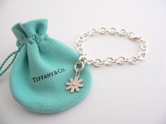 Overview: Here is a gift that she will surely adore! It is shiny, stylish, and super versatile! This piece will make someone REALLY happy! :) Offered for sale is a wonderful Tiffany & Co. Sterling Silver and Pink Enamel Daisy Charm Bracelet. Hanging from its bright Tiffany silver chain is a very pretty Pink Enamel Daisy charm! A classic Tiffany piece that any girl will adore! The Daisy charm hangs from its Sterling Silver Tiffany clasp - it is removable from the bracelet and thus allows you to w Luxury Flower-shaped Bracelets As Gift, Luxury Hallmarked Charm Bracelet Gift, Luxury Sterling Silver Charm Bracelet Gift, Luxury Sterling Silver Charm Bracelet As A Gift, Luxury White Gold Charm Bracelet Gift, Designer Bracelets With Polished Finish For Gift, Designer Polished Finish Bracelets For Gift, Elegant Polished Charm Bracelet Gift, Elegant Charm Bracelet As Gift With Polished Finish