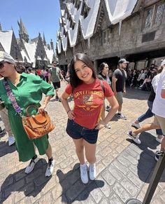 two women standing in front of a castle with lots of people walking around the area