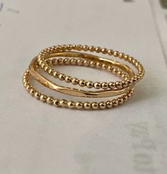 Dripping in gold, these Stacking Rings are the ultimate statement pieces every fashionista will fall for. This triple treat comprises a thumb ring, ball ring, and bead ring, each showcasing an unmatched charm. Considering a lavish gift for a birthday? Look no further, these Gold-filled beauties ensure smiles all around. Adjustable Double Band Stackable Rings For Promise, Adjustable Double Band Stackable Promise Rings, Dainty Stacked Rings As A Gift, Stacked Ring Jewelry Gift, Gift Double Band Stackable Bands, Adjustable Stacked Gold Midi Rings, Adjustable Double Band Gift Bands, Gift Stackable Double Band, Stacked Round Beads Jewelry For Gift