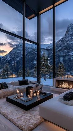 a living room filled with lots of furniture and large windows overlooking the snow covered mountains