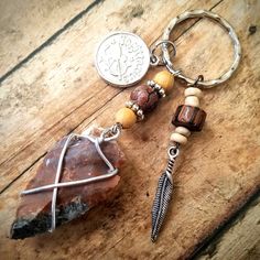 a key chain with a stone, feather and bead charm hanging from it on a wooden surface