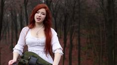 a woman with red hair is holding a green skateboard in the middle of a wooded area