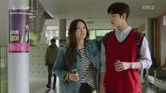 a man and woman standing next to each other in an airport lobby with people walking by