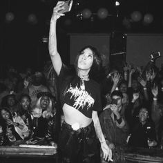 a black and white photo of a woman with her arms in the air at a concert