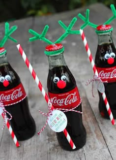 three coca - cola bottles with reindeer noses and candy canes tied to the top