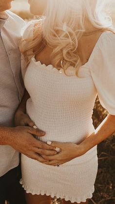 a man and woman standing next to each other with their hands on their stomachs