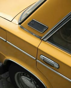 an old yellow car is parked on the street