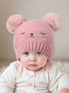 a baby wearing a pink knitted bear hat