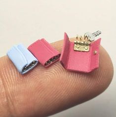 two miniature pink and blue lighters sitting on top of each other's finger