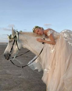 a woman in a wedding dress riding on the back of a white horse