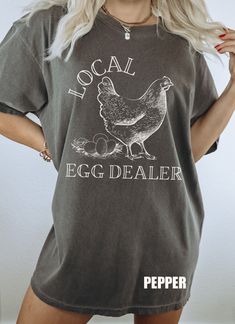 Very trendy Local Egg Dealer Shirt. Made on a vintage looking Color Comforts T shirt. To get the oversized look we recommend ordering 2 sizes up. Comfort Colors introduces its garment-dyed t-shirt; a fully customizable tee made 100% with ring-spun cotton. The soft-washed, garment-dyed fabric brings extra coziness to your wardrobe while the relaxed fit makes it an excellent daily choice. The double-needle stitching throughout the tee makes it highly durable while the lack of side-seams helps the Spring Acid Wash Relaxed Fit T-shirt, Oversized Distressed Cotton T-shirt, Spring Grunge Short Sleeve Shirt, Distressed Graphic Tee Shirt In Relaxed Fit, Distressed Cotton Short Sleeve Shirt, Distressed Graphic Tee With Relaxed Fit, Distressed Cotton Shirt With Short Sleeves, Distressed Relaxed Fit Summer Shirt, Summer Distressed Relaxed Fit Shirt