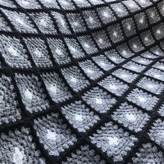 a black and white crocheted blanket with squares on it's sides, in the shape of hearts