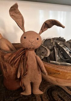 a stuffed rabbit sitting next to an old pair of wrenches in a wooden bowl