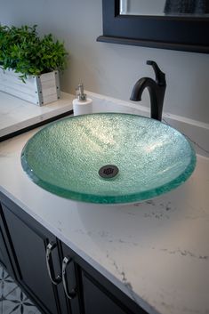 a bathroom sink sitting on top of a counter next to a green glass bowl under a faucet