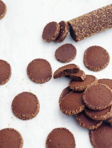 chocolate cookies are arranged on a white surface next to a rolled up corkscrew