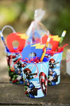 captain america themed cups with toothbrushes and pencils in them on a picnic table