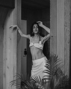 a black and white photo of a woman in a bathing suit standing by a door