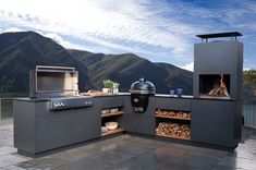 an outdoor bbq with grill, oven and firewood on the outside patio overlooking mountains