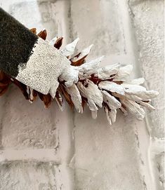 a close up of a pine cone on a white brick wall with snow flakes