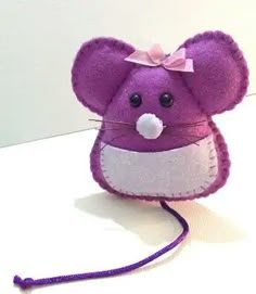 a purple mouse with a pink bow on it's head sitting on a white surface