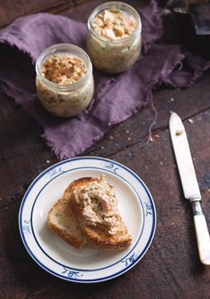 two pieces of bread on a blue and white plate next to some jars with food in them