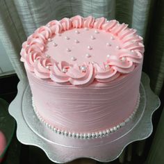 a pink frosted cake sitting on top of a table