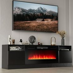 an entertainment center with a large television mounted on the wall and a fire place in front of it