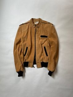 "Suede Leather Jacket Size: Men's Small Era: 1980's Material: Suede Leather  Made in Mexico Details: Light Brown Suede Leather Jacket with Black Cotton Wrist and Waist Cuffs and Pocket Trim.  Mideal Zipper  Great Condition with Minimal Wear.  No Defects, Holes, or Stains.  Chest (Armpit-Armpit) : 21\"  Sleeve (Shoulder-SleeveEnd) : 25\" Length (Neckline-Bottom) : 24\""