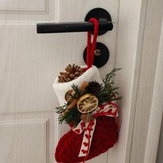 a christmas stocking hanging on the front door with pine cones, cinnamons and an orange slice