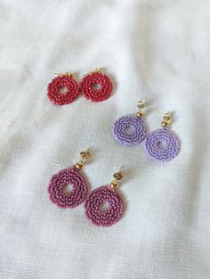 three pairs of beaded earrings sitting on top of a white cloth