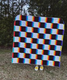 a large multicolored quilt sitting in the grass