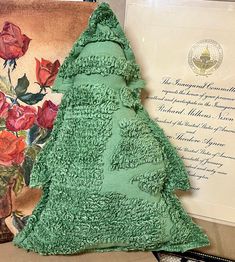 a green christmas tree made out of cake next to a framed letter and painting with roses on it