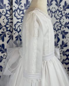 A gorgeous traditional white and long sleeves dress for girls to wear on her communion day. This is a stunning piece made with a white organza and with handmade details throughout the gown; it has pleats, laces, and elegancy. It has buttons and a bow on the back. Dry Clean Lining: 100% cotton Made in Spain Final Sale, no exchanges nor returns will be accepted The Sizing Chart measurements are in centimeters First Communion Dress With Lace Bodice In Organza, Fitted Organza First Communion Dress With Lace Bodice, Elegant Confirmation Dress With Lace Sleeves, Elegant Dress With Lace Sleeves For Confirmation, Organza Baptism Dress With Lace Bodice For First Communion, Elegant Organza Baptism Dress For Ceremony, Elegant First Communion Dress With Ruffles, Elegant Tulle Baptism Dress With Satin Bow, Elegant First Communion Gown With Lace Sleeves