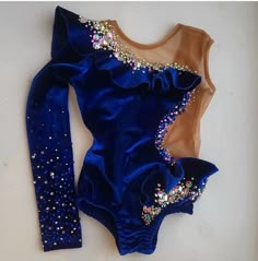 a blue bodysuit with gold sequins on the bottom and sleeves, sitting on a white surface