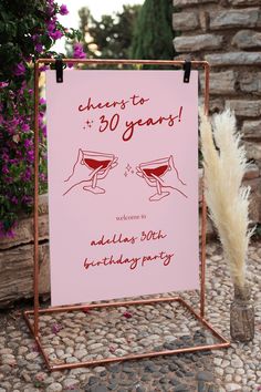 a pink sign that says cheers to 30 years with two champagne glasses in front of it