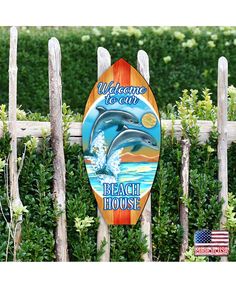 a wooden sign that says welcome to the beach house with a dolphin jumping out of it