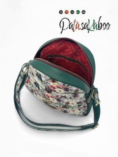 a small purse with floral print on the front and green strap, sitting on top of a white surface