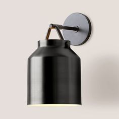 a black and white light fixture on a wall next to a gray wall mounted lamp