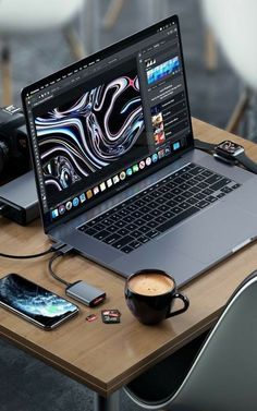 an open laptop computer sitting on top of a wooden desk next to a cup of coffee