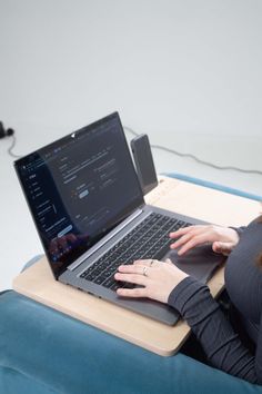 a woman sitting on a couch using a laptop computer with her hands resting on the keyboard