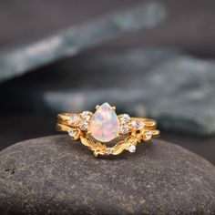 an opal and diamond ring sitting on top of a rock