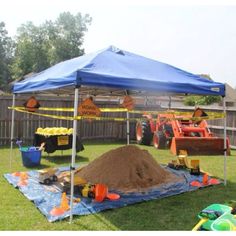 a blue tent sitting on top of a lush green field next to a pile of dirt